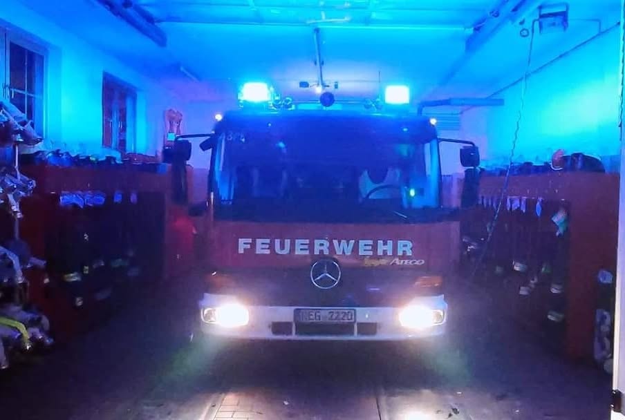 Löschfahrzeug mit eingeschaltetem Blaulicht in der Fahrzeughalle